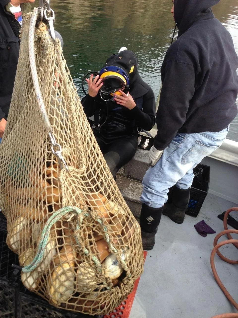 Bettina on a boat with a geoduck net bag